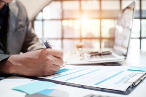 Former spouses review insurance papers, vehicle documents, and a home policy at a kitchen table.