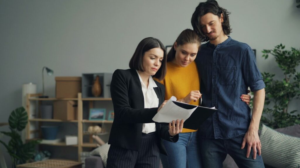 Homeowner reviews insurance documents beside a laptop, house keys, and a folder of property records.